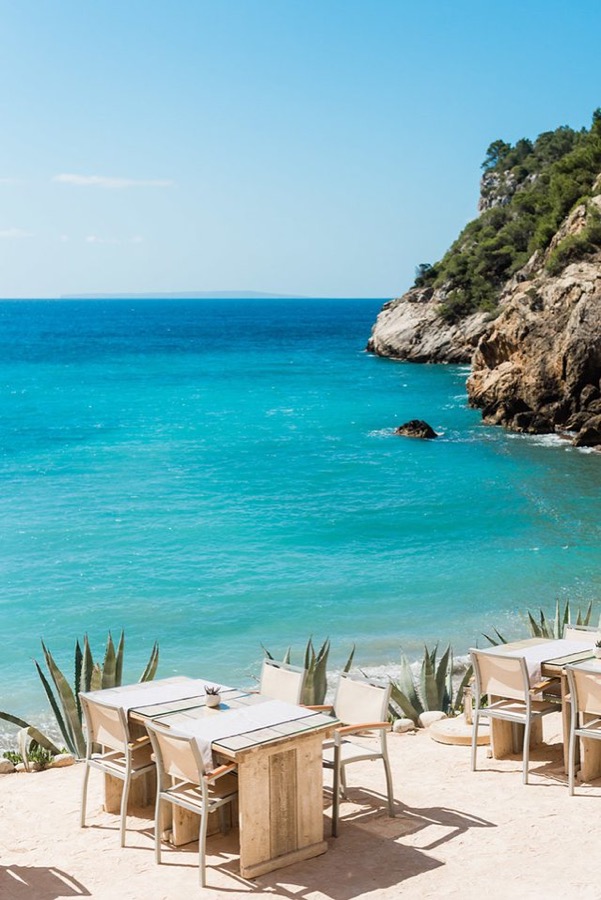 Tables set on a terrace above a turquoise bay